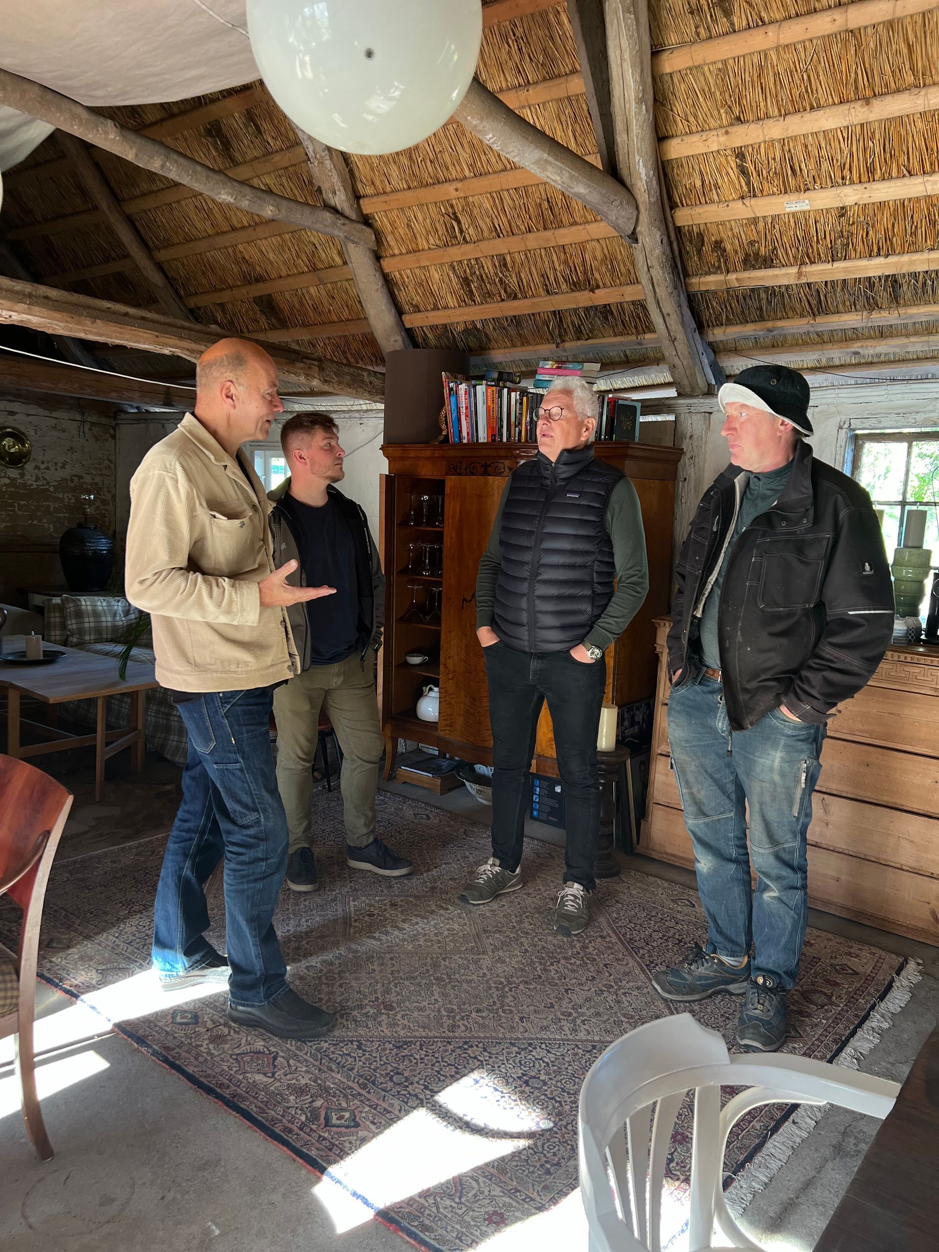 A group of men are standing in a room talking to each other.