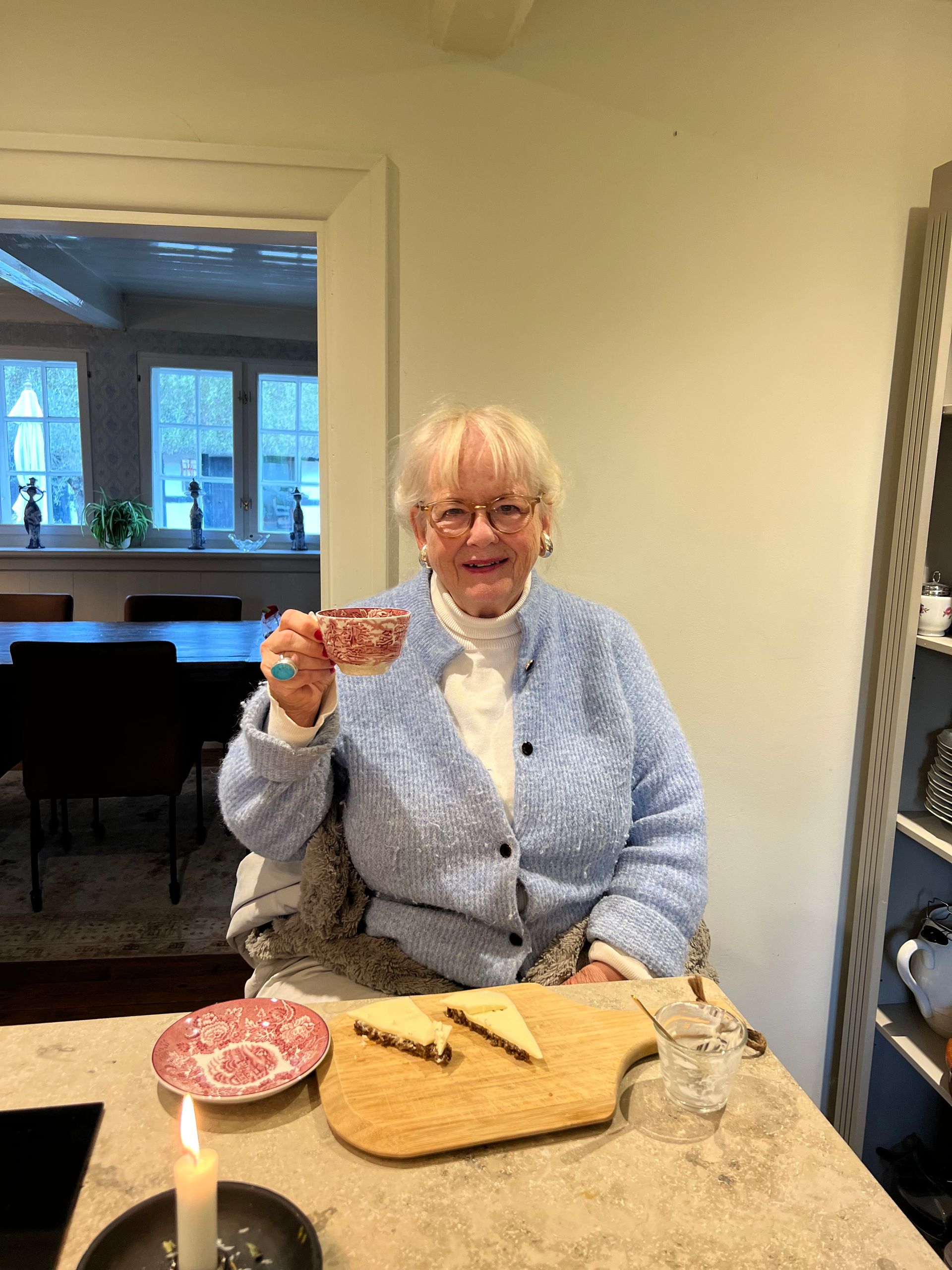 A woman is sitting at a table holding a cup of coffee.