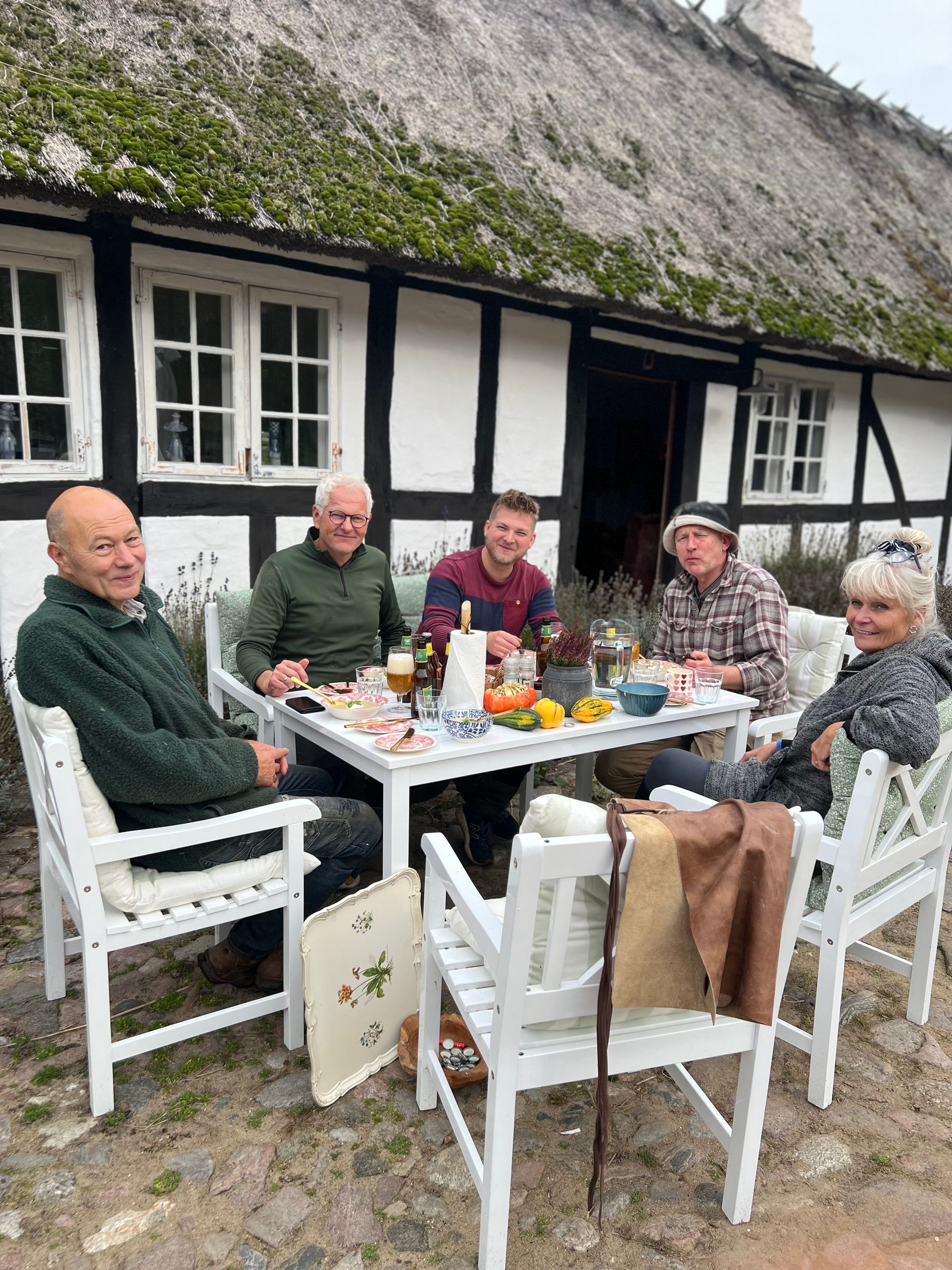 A group of people are sitting at a table outside of a house.