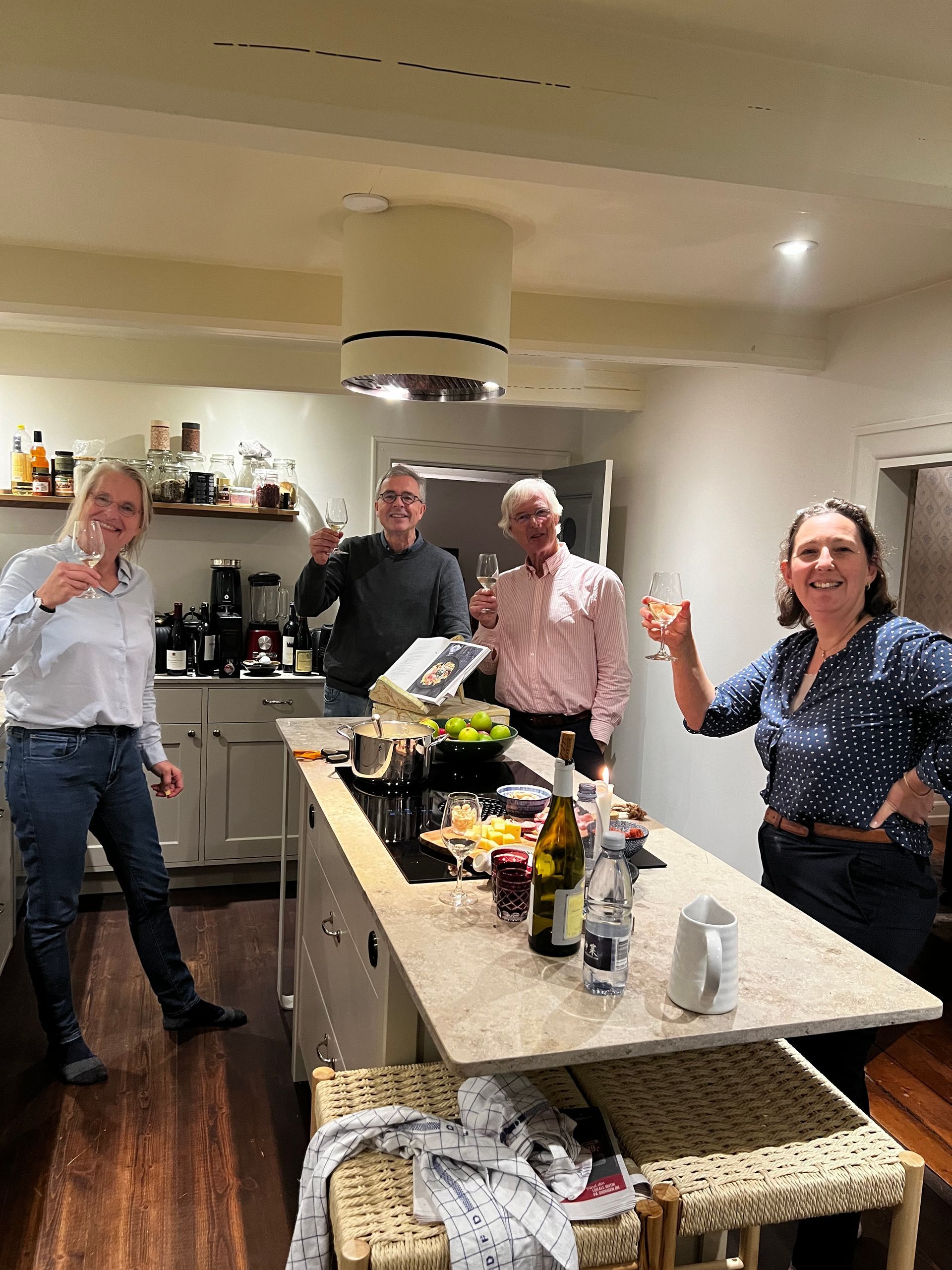 A group of people are standing around a table in a kitchen.