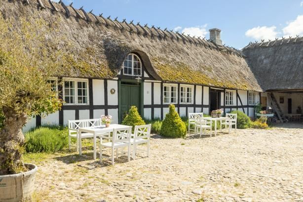 A thatched roofed house with a table and chairs in front of it.