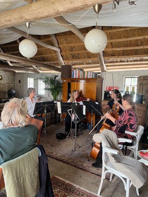 A group of people are sitting in a room playing instruments.