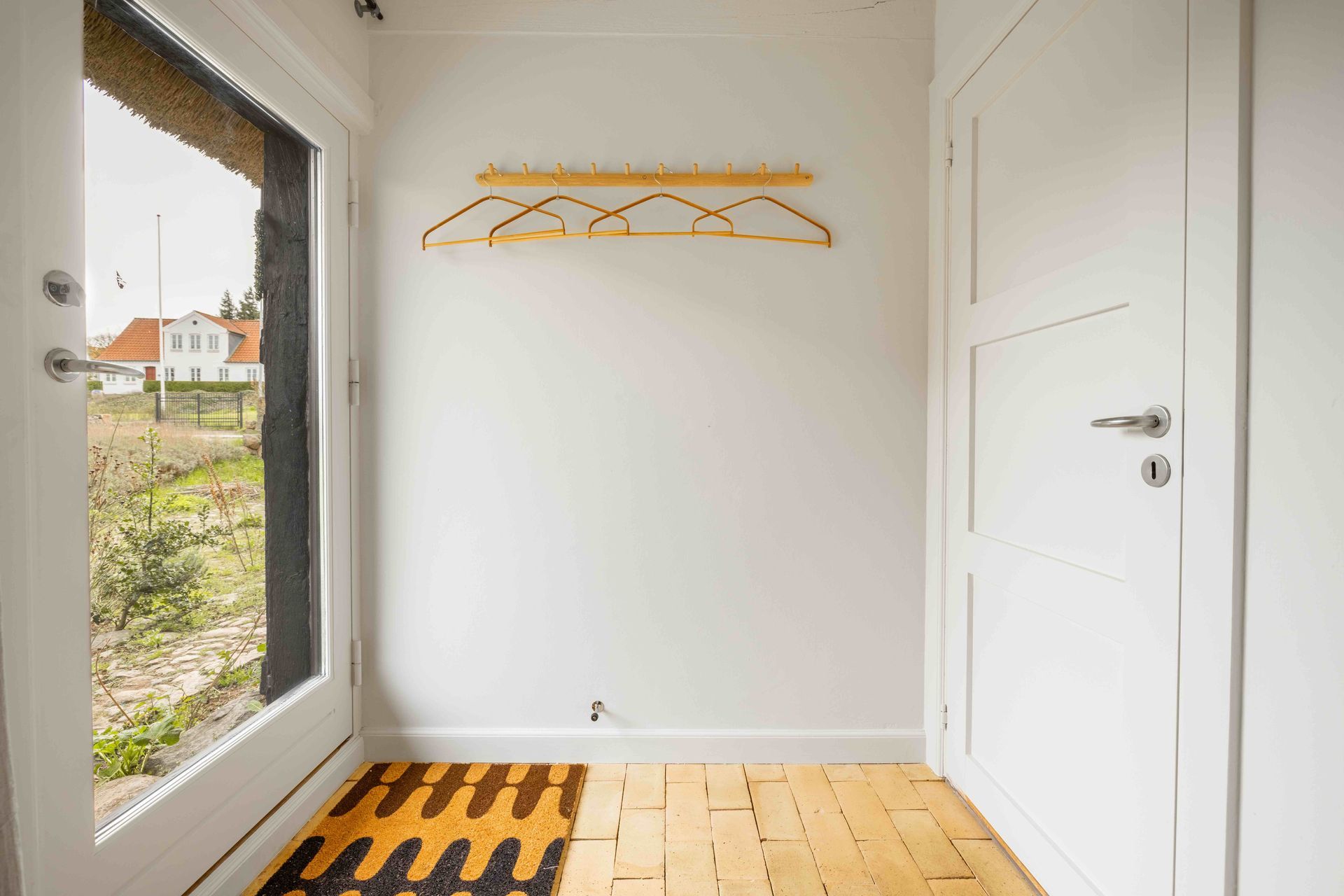 A hallway with a rug on the floor and a window.