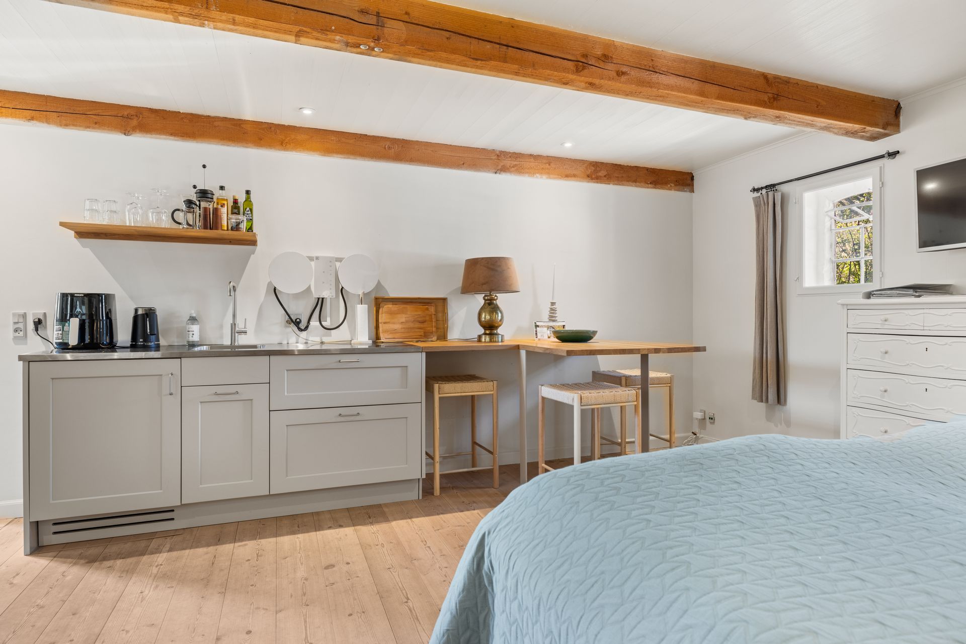 A bedroom with a bed , kitchen , table and television.