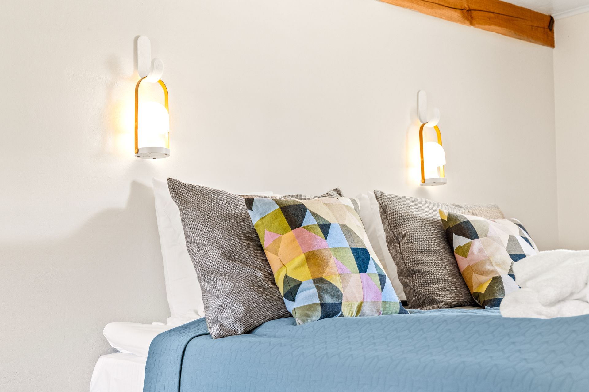 A bed with a blue blanket and pillows in a bedroom.