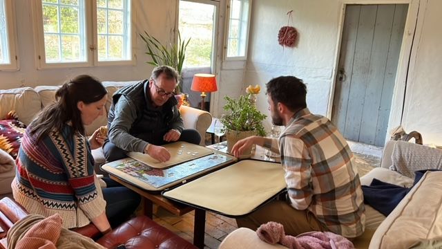 A group of people are sitting around a table in a living room.