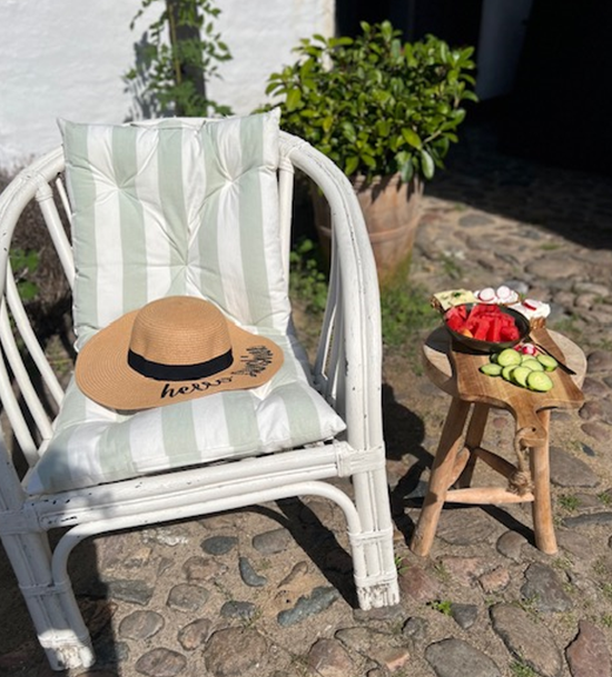 A chair with a hat on it and a stool with food on it.