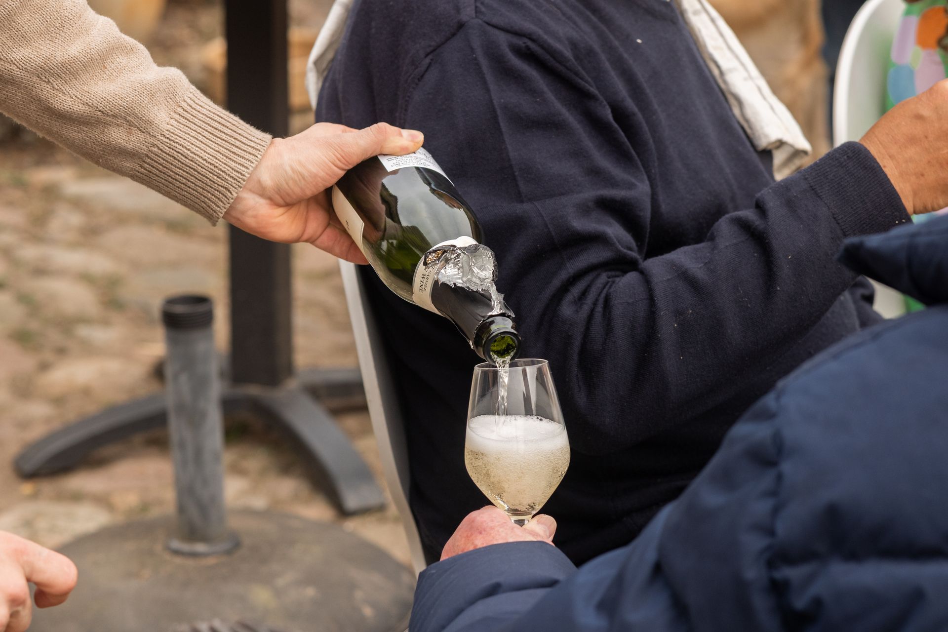 A person is pouring a glass of champagne from a bottle.