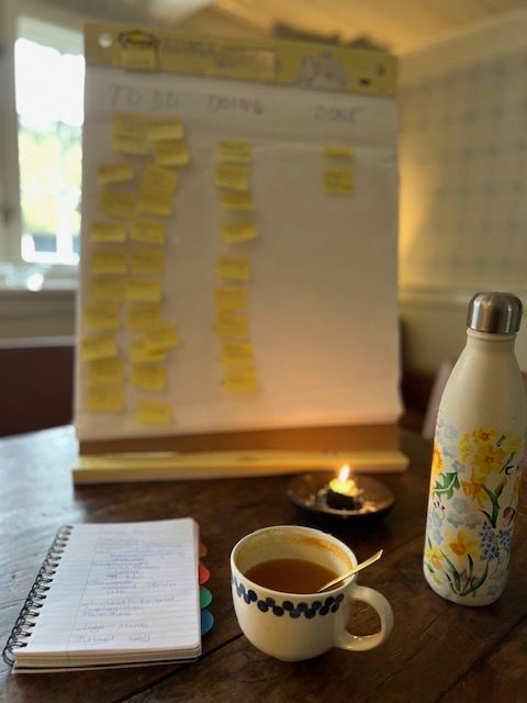 A cup of tea sits on a table next to a notebook and a water bottle