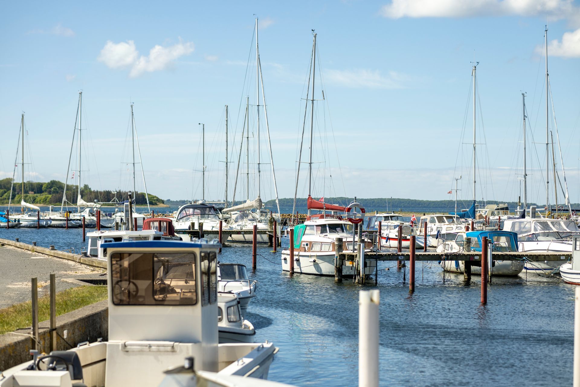 A row of boats are docked in a marina on a sunny day.