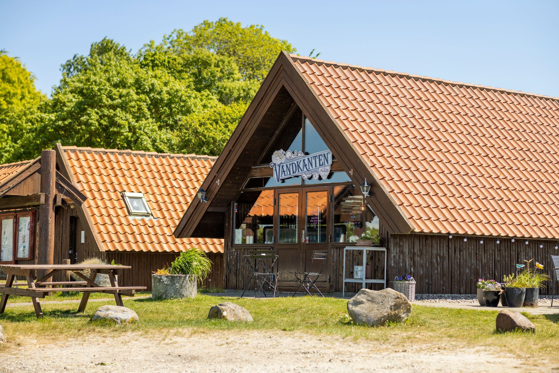 A large wooden building with a red tiled roof and a picnic table in front of it.