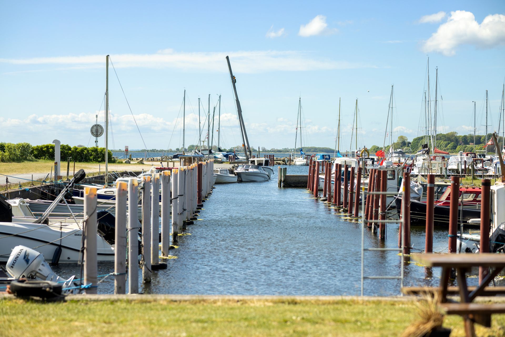 A row of boats are docked in a marina on a sunny day.