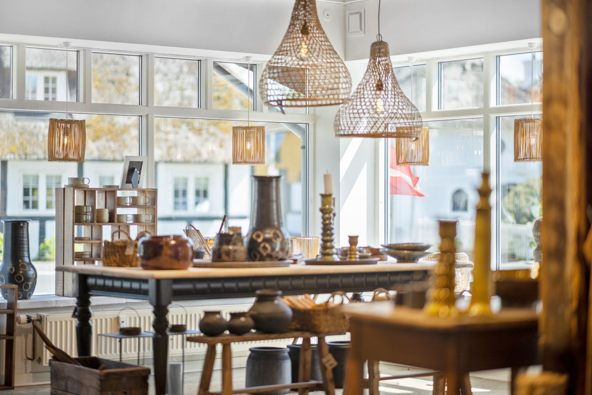 A room with a table and vases on it and a lot of windows.
