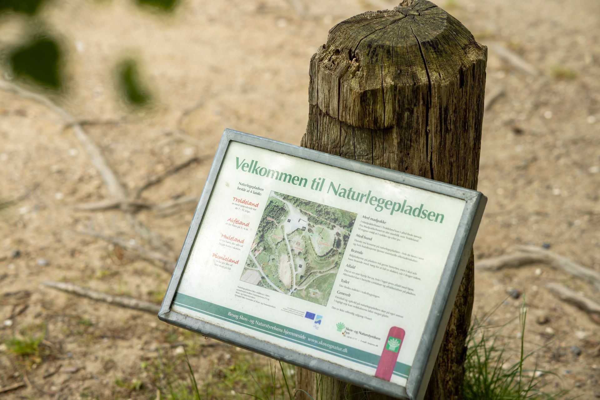 A sign is sitting on top of a wooden post.