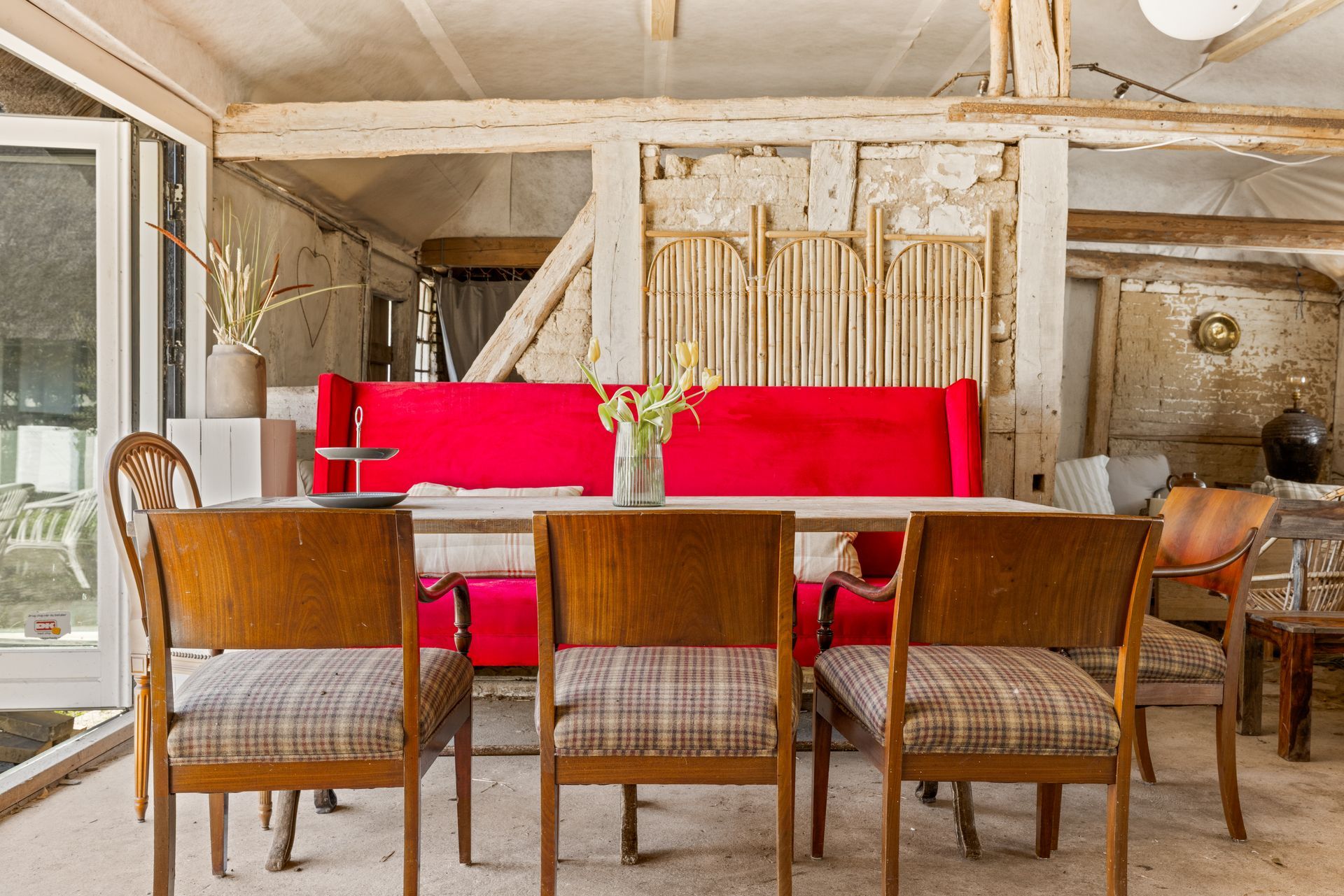 A dining room with a table and chairs and a red couch.