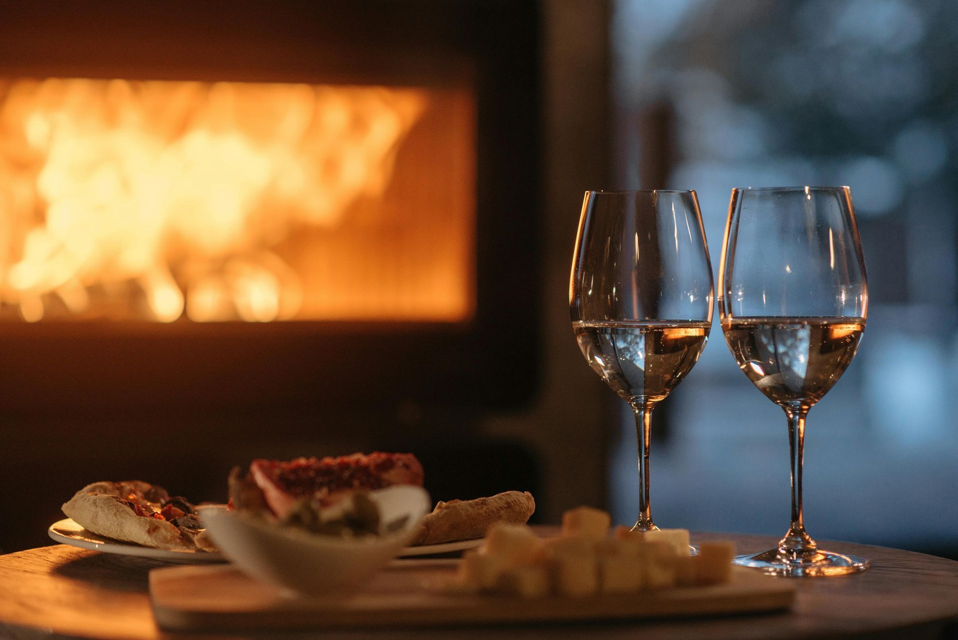 Elegant glas vin og tapas ved pejsen – intim madoplevelse på Solbjerggaard. Elegant glass of wine and tapas by the fireplace – intimate dining experience at Solbjerggaard.