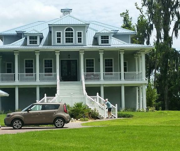 A car is parked in front of a large house