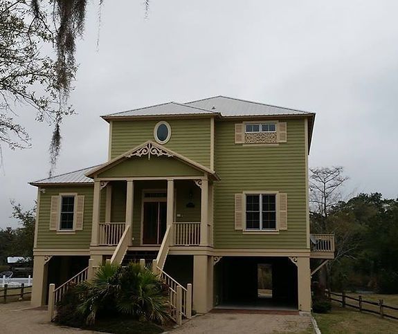 A green house with a white roof and a porch