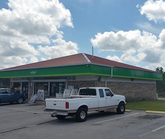 A white truck is parked in front of a green building.
