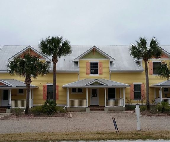 A yellow house with palm trees in front of it