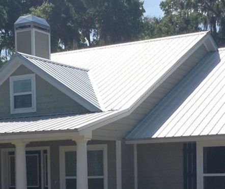 A house with a white metal roof and a chimney
