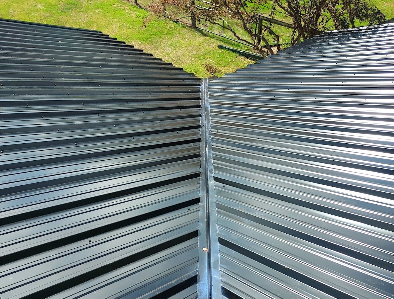 A close up of a metal fence with a grassy field in the background.