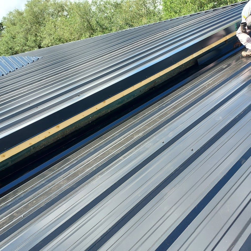 A man is standing on top of a black metal roof
