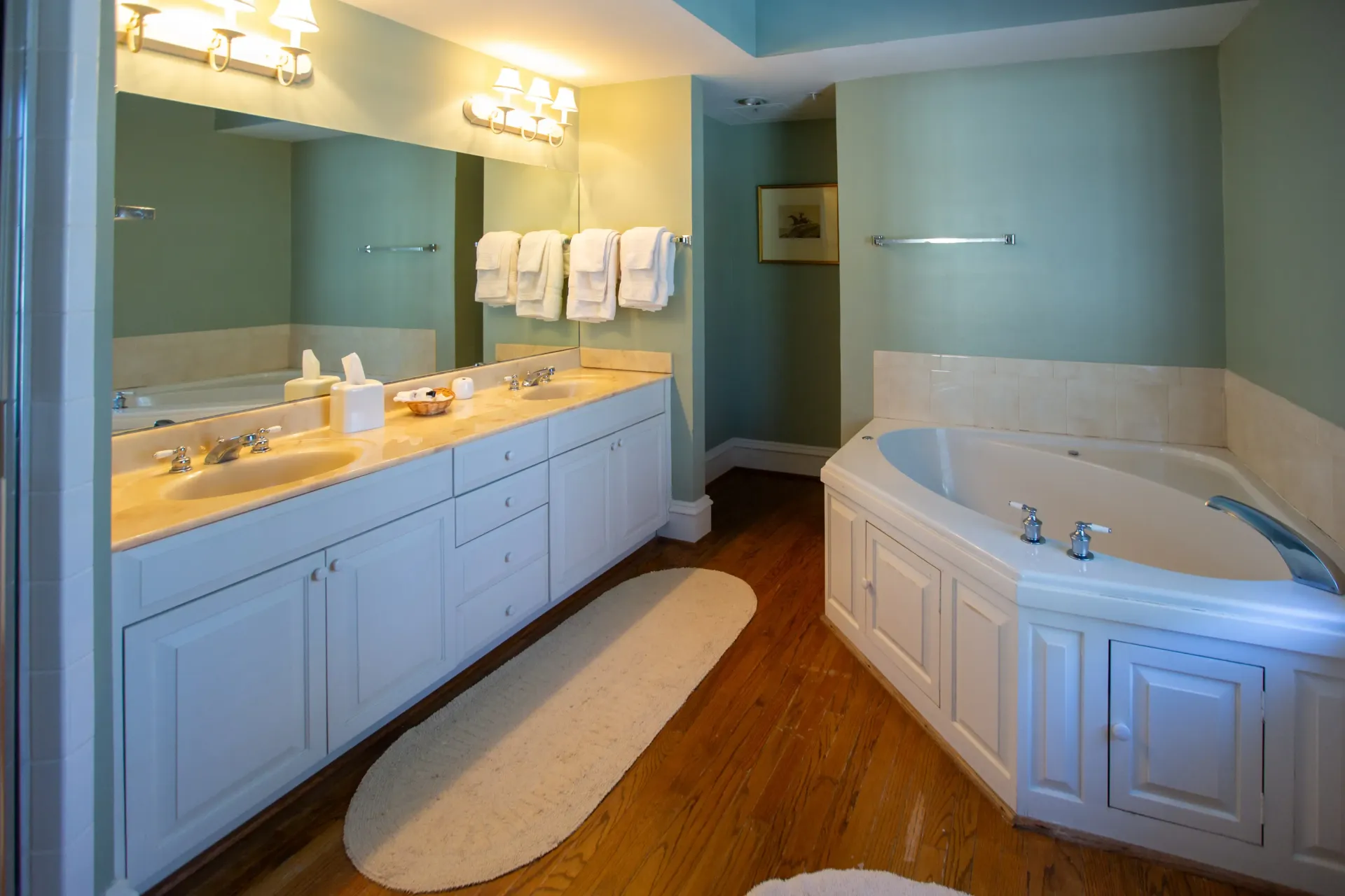 Spacious bathroom with white cabinetry, light blue walls, a bathtub, and a double vanity.