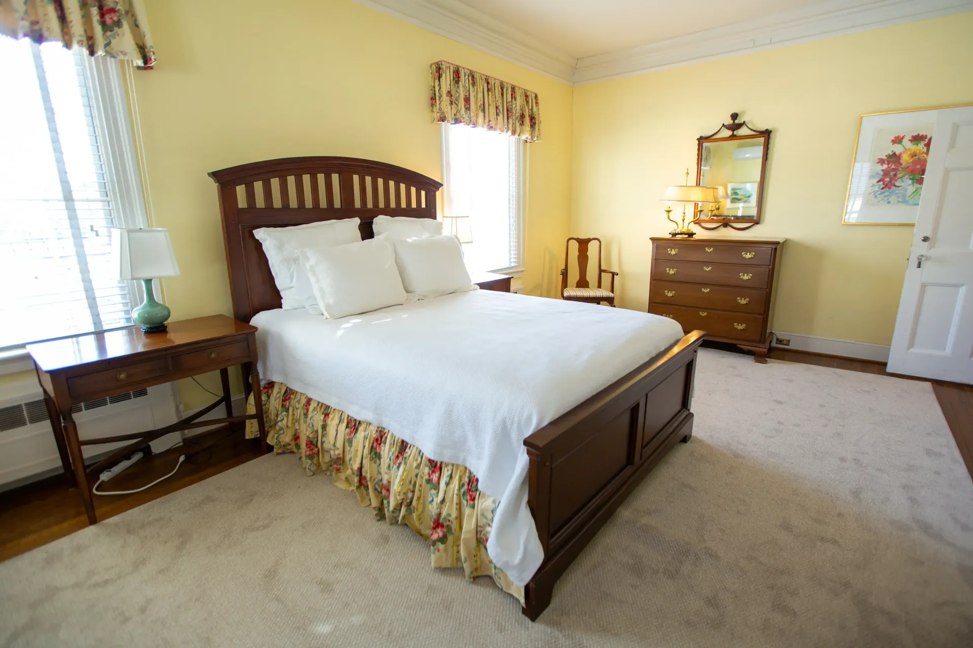 Bedroom with bed, nightstand, dresser, and mirror; yellow walls, cream carpet.