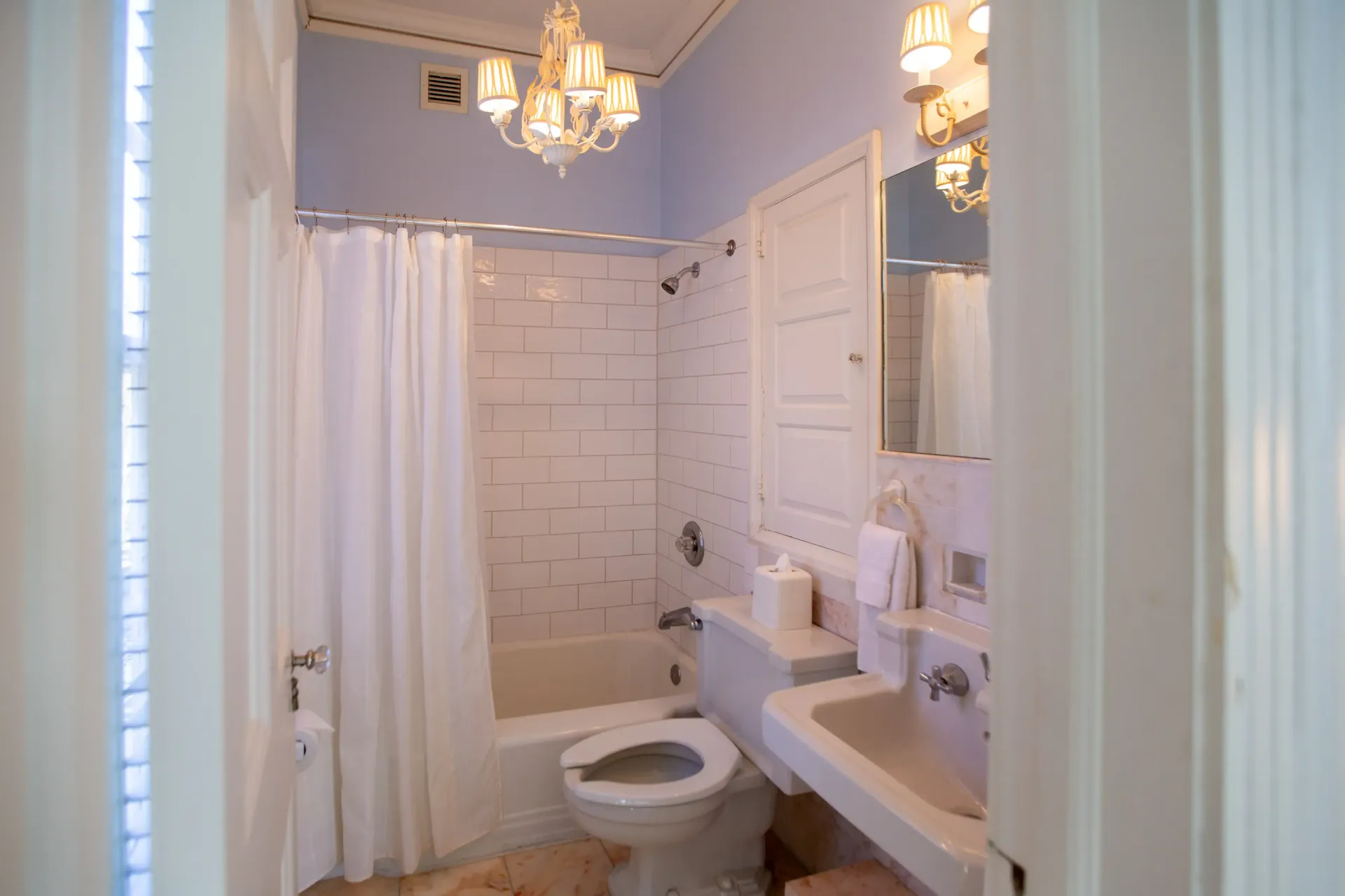 Bathroom with white fixtures, shower curtain, and a chandelier.