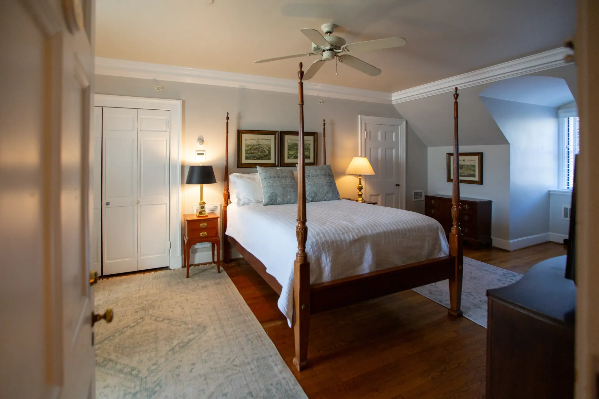 Bedroom with a four-poster bed, nightstands, and a ceiling fan. Light-colored walls and hardwood floors.