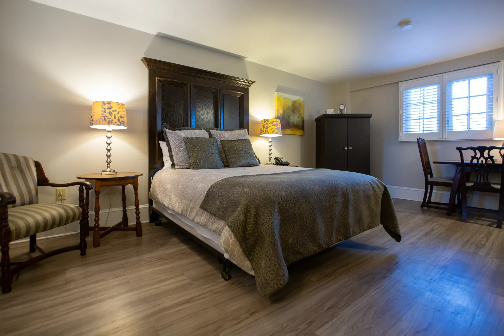 Bedroom with bed, nightstands, chair, wardrobe, small dining table, and window.