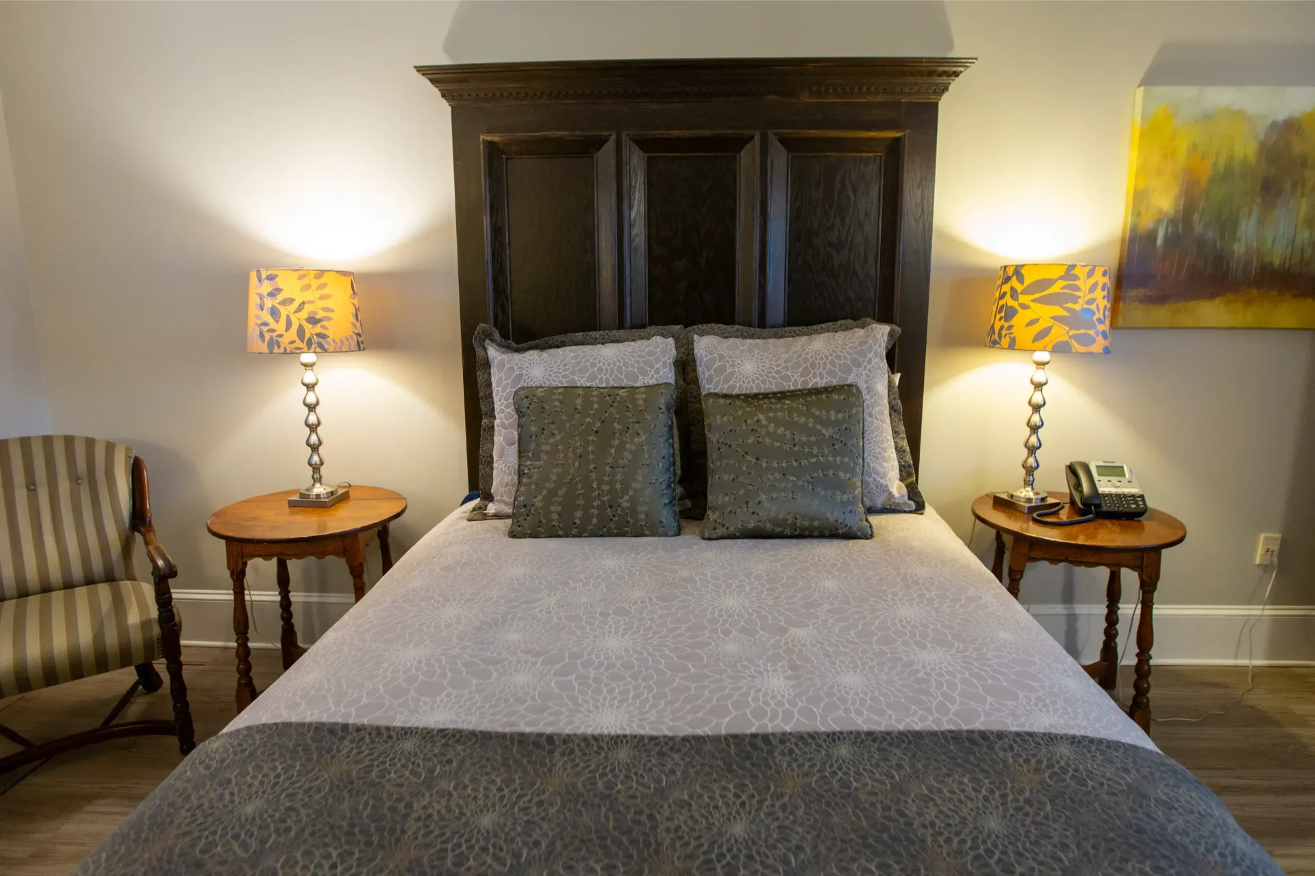 Bedroom with a bed, two lamps, two side tables, and a chair.