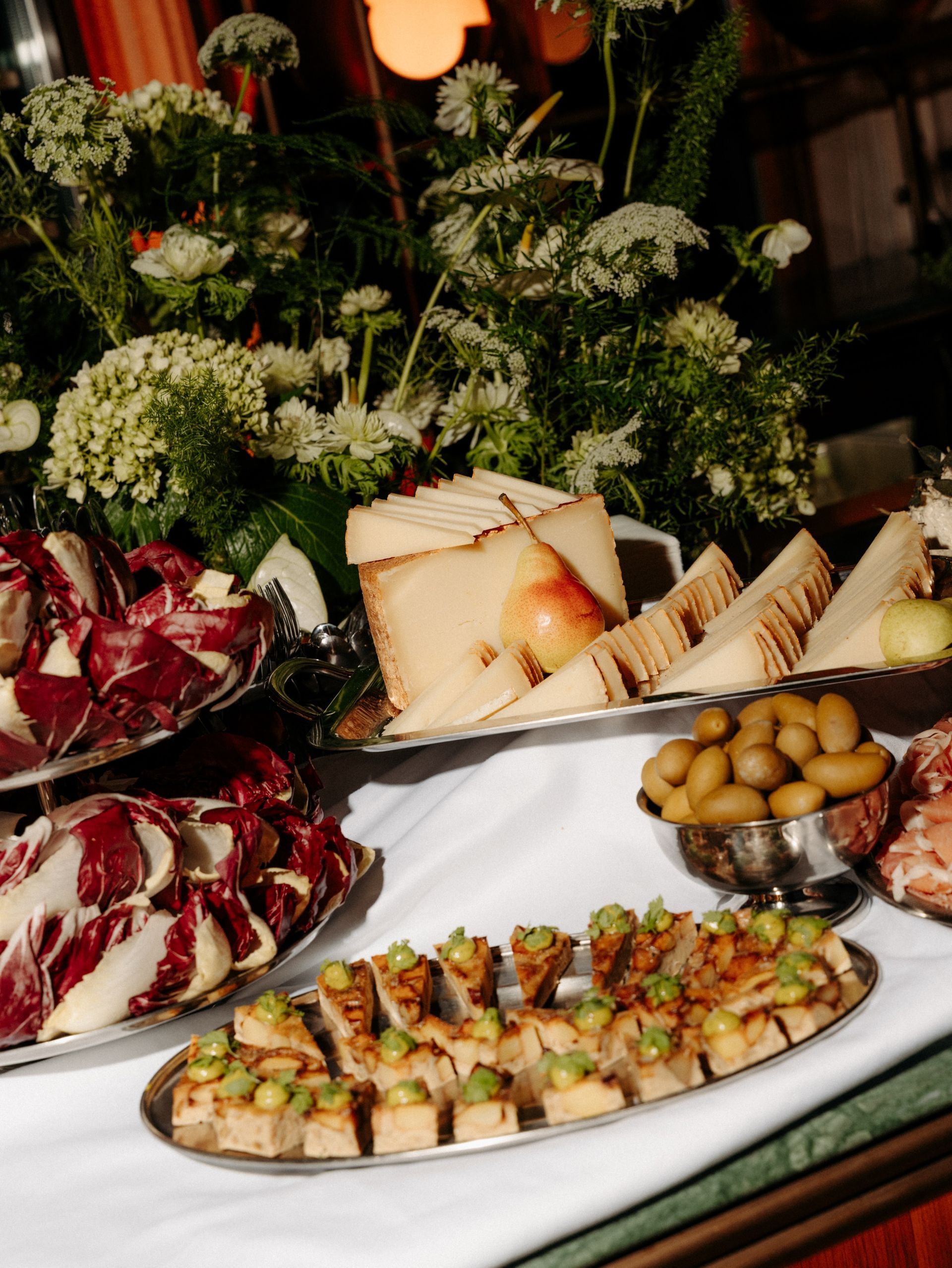 Hand holding a martini glass with a green olive, red nail polish.