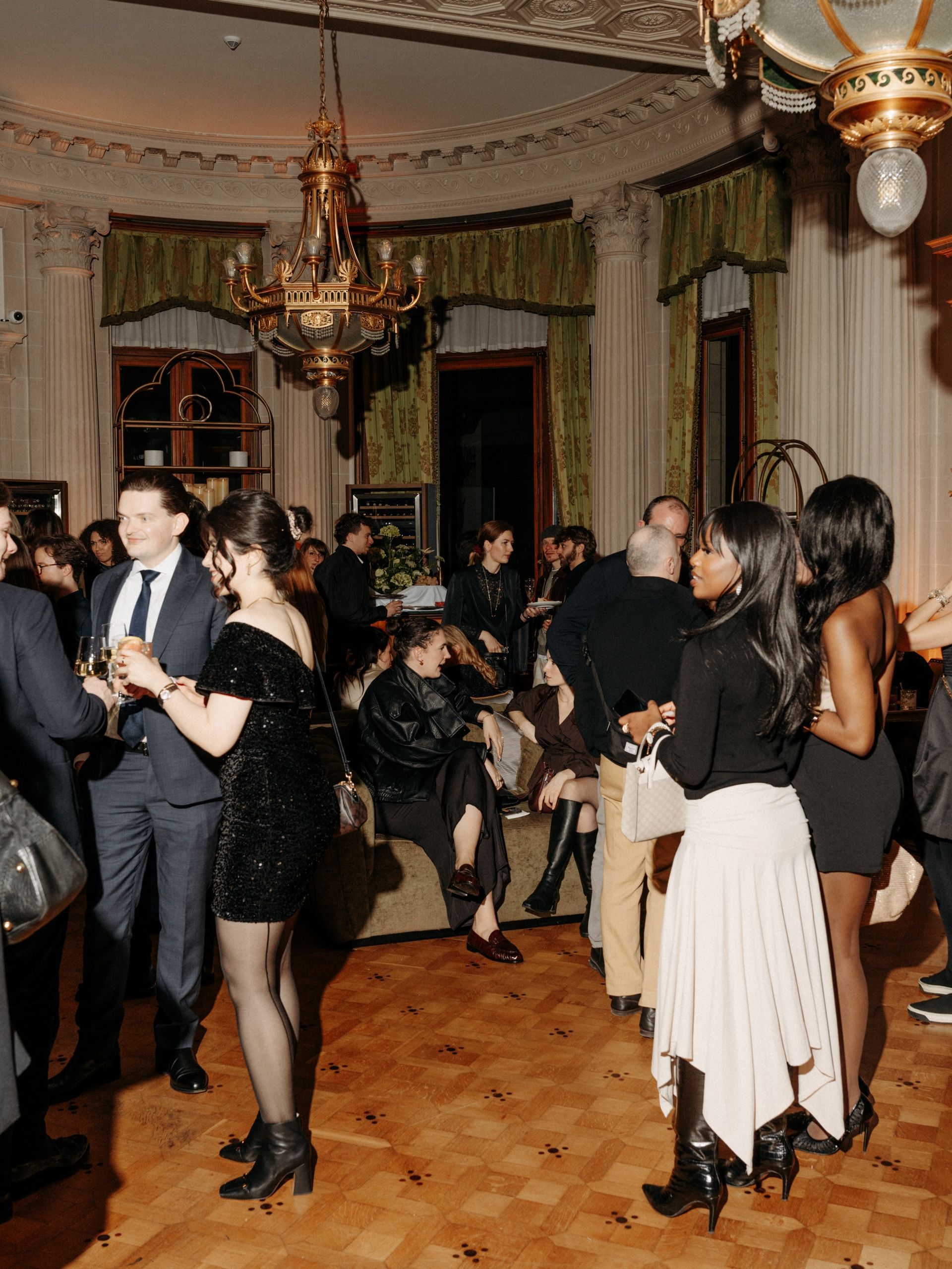 Three friends laughing and dancing in a dimly lit setting; one wears a sequined dress.