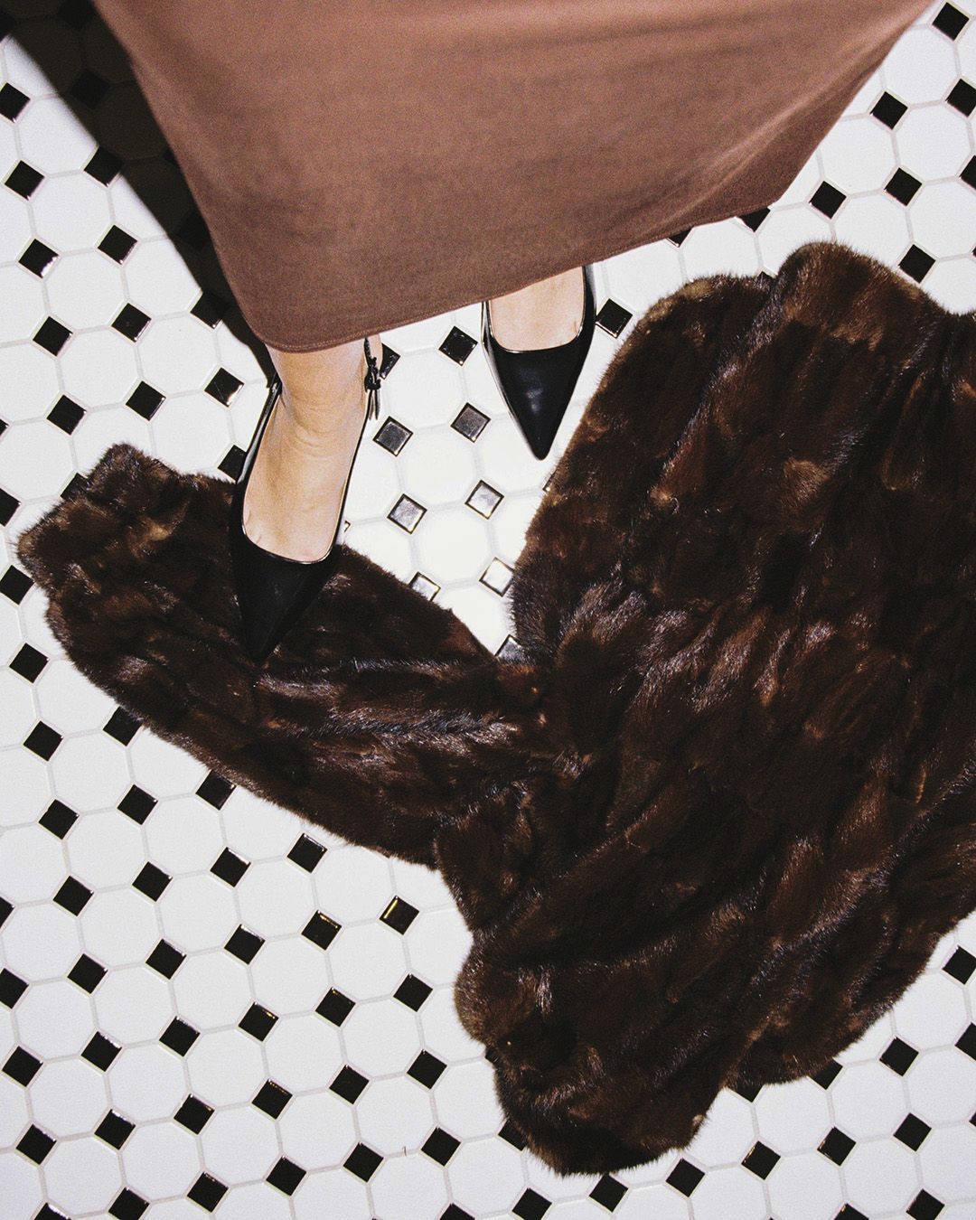 Hand holding a martini glass with a green olive, red nail polish.