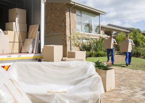 Movers carrying cardboard boxes from house to moving van
