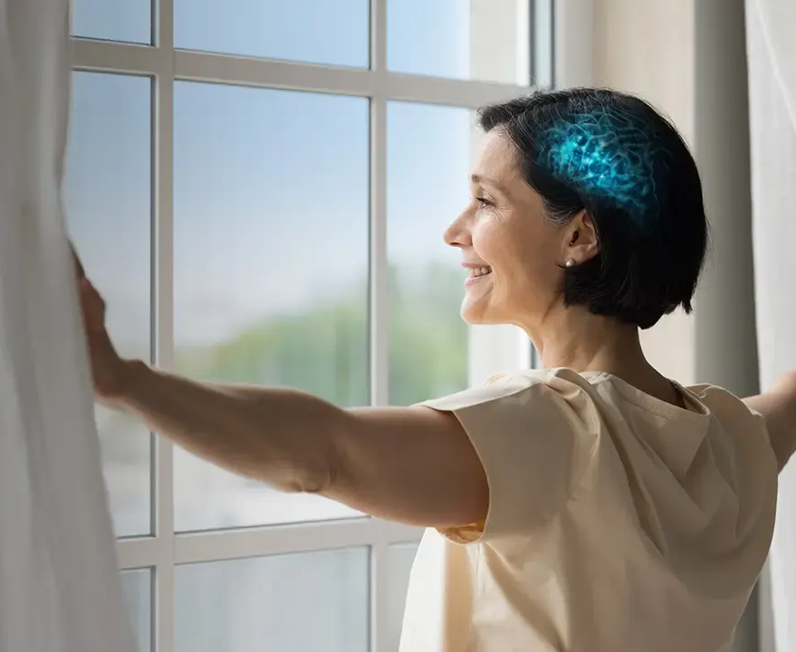 Donna sorridente con elegante acconciatura raccolta, che indossa un abito bianco con dettagli di piume e perle.