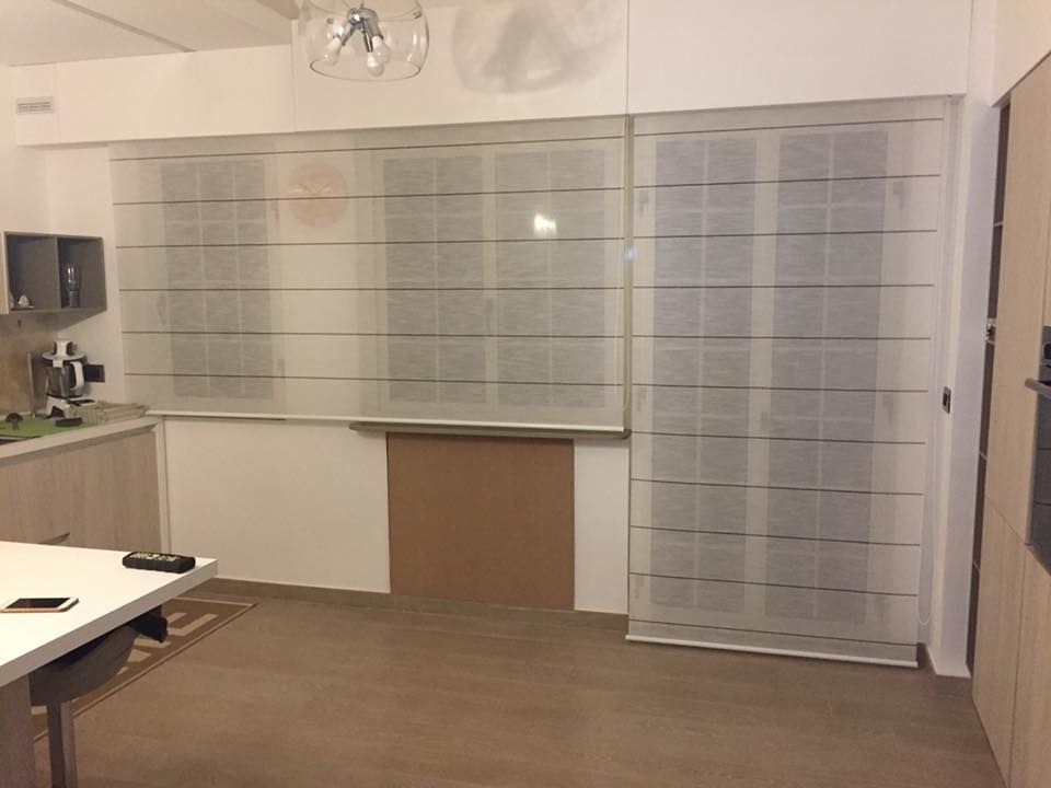 Stanza vuota con grandi finestre smerigliate, una parete bianca e un pavimento in legno.