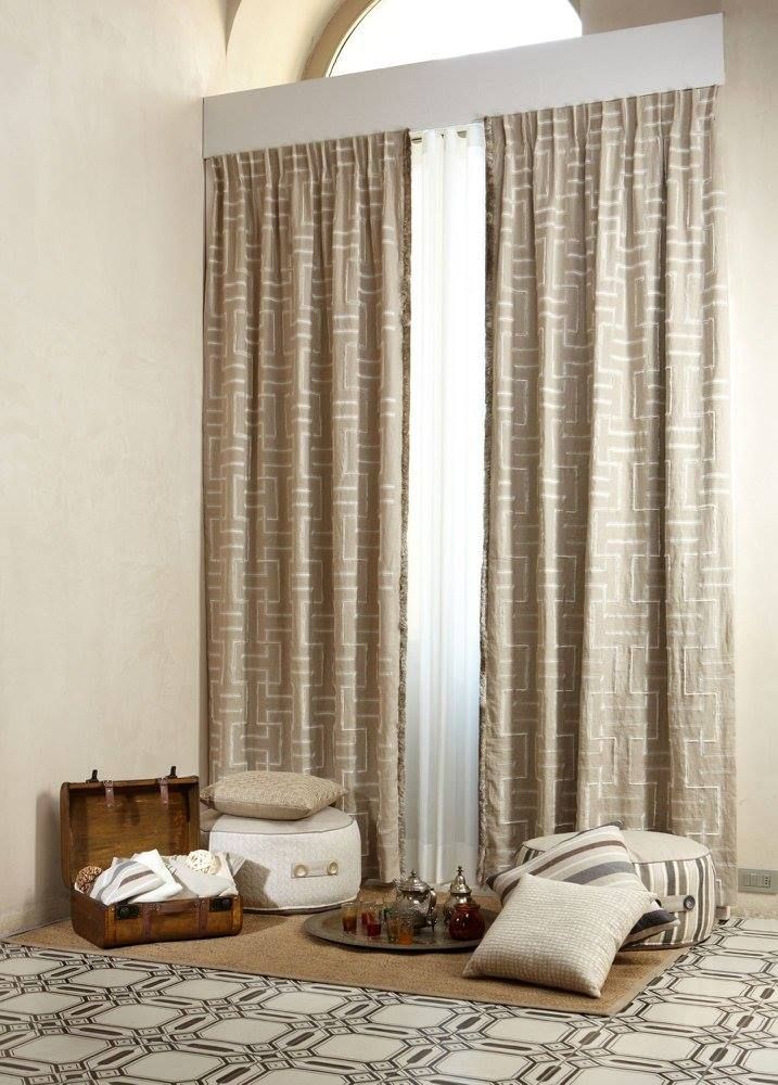 Accogliente soggiorno con tende beige, cuscini da pavimento e cesti portaoggetti intrecciati su un tappeto.