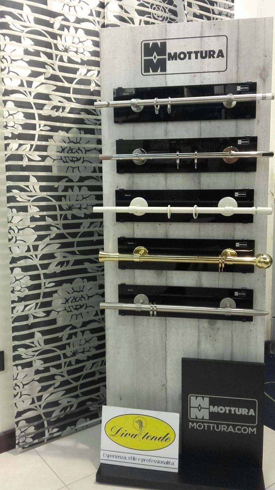 Esposizione di bastoni e terminali decorativi in ​​metallo per tende in uno showroom, con uno sfondo a parete decorato.
