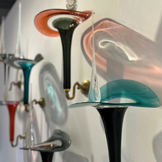 Colorful glass sconces mounted on a white wall; cast shadows.