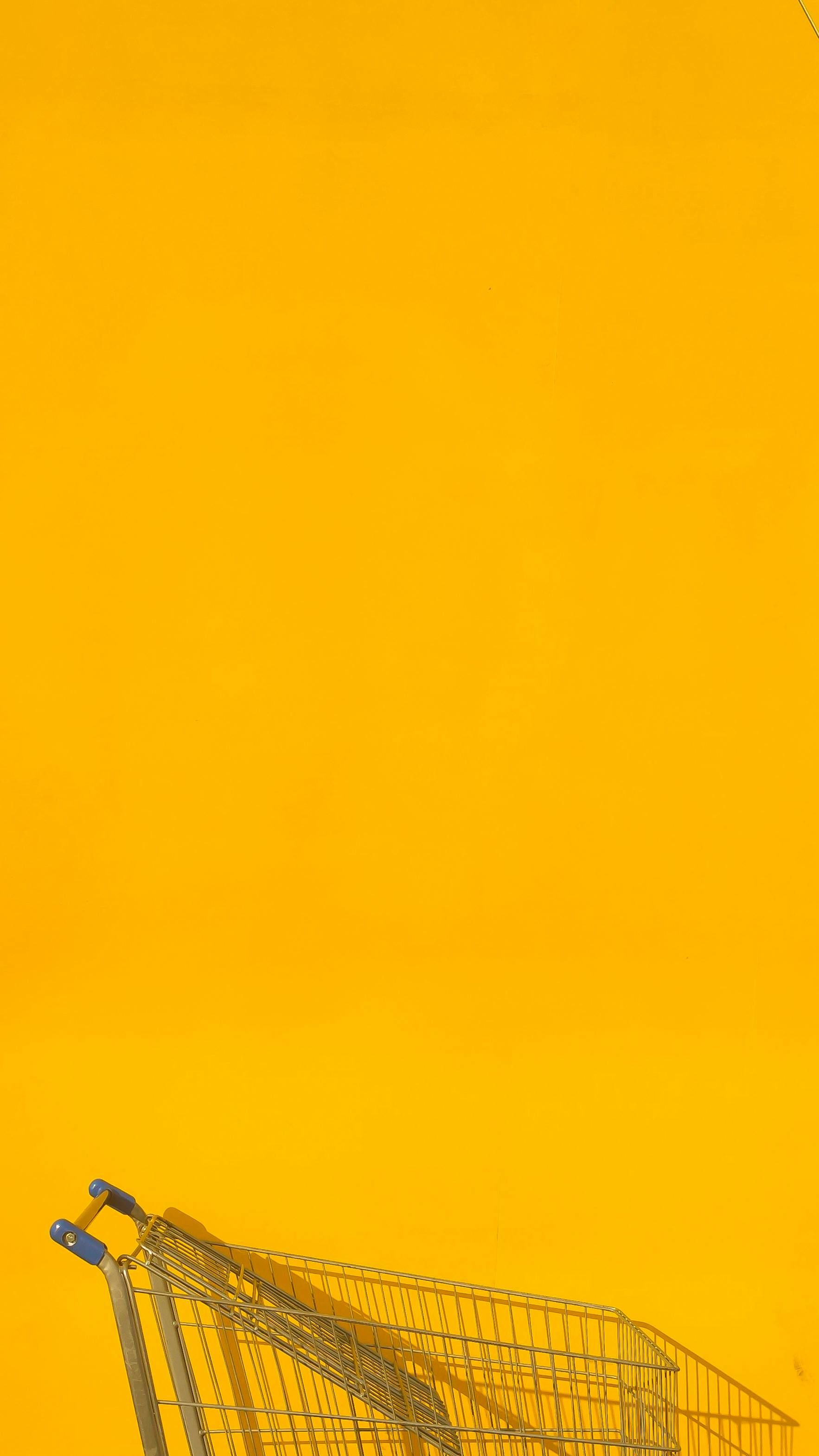 A shopping cart is sitting on a yellow background.