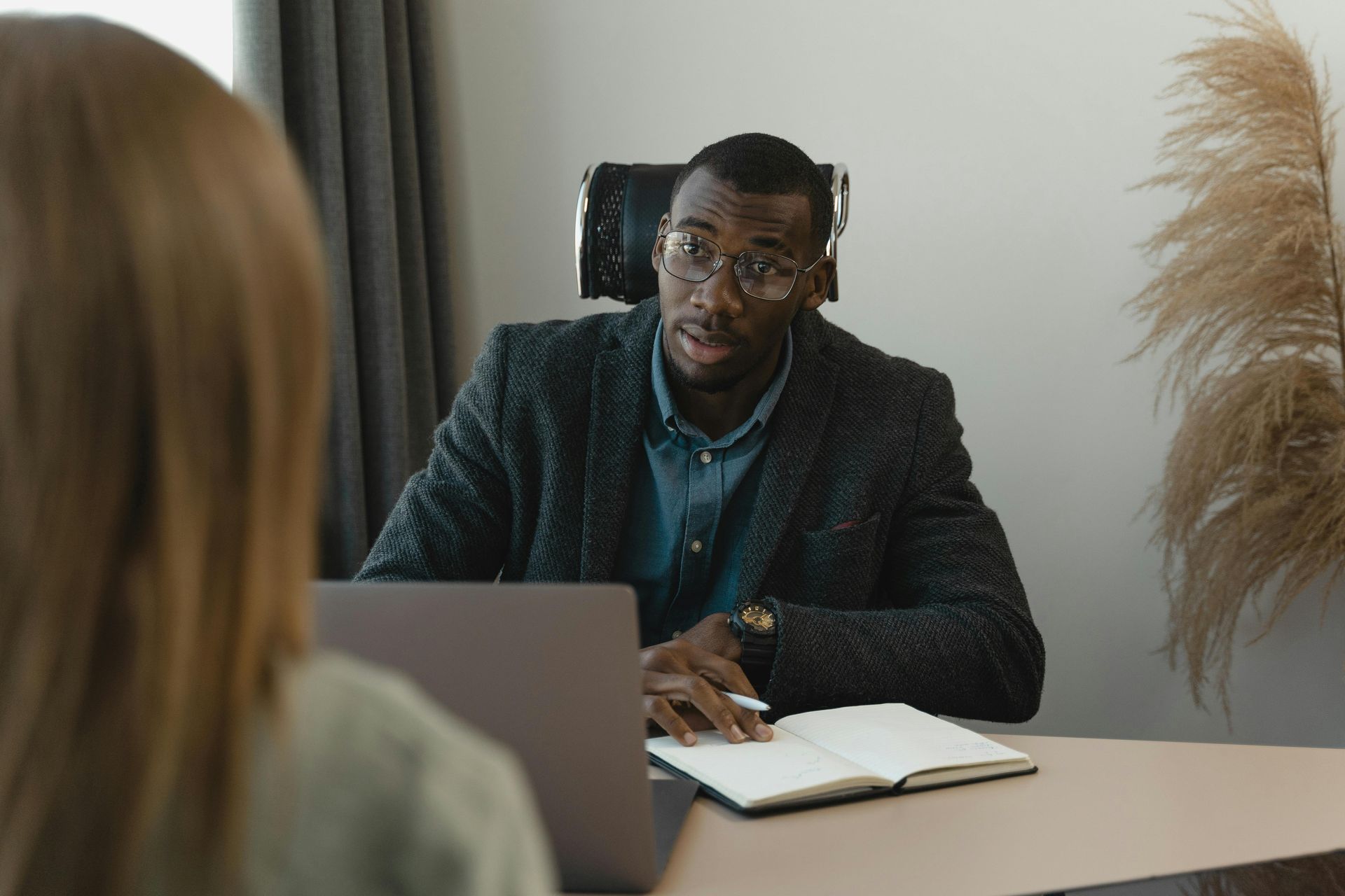 Man interviewing person at desk, taking notes.