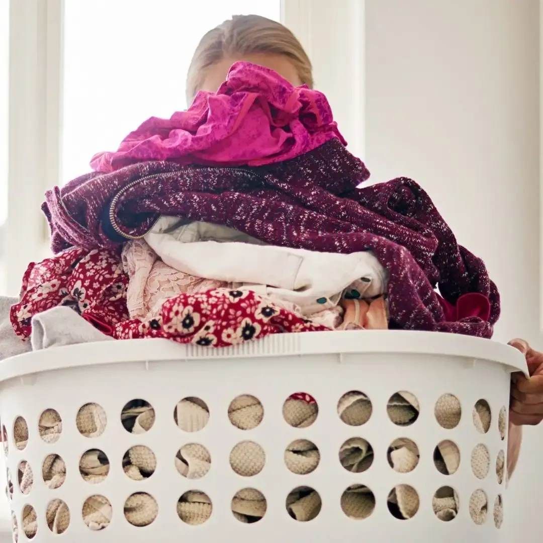 A Woman Is Holding A Laundry Basket Full Of Clothes — Carwash 44 In Caboolture, QLD