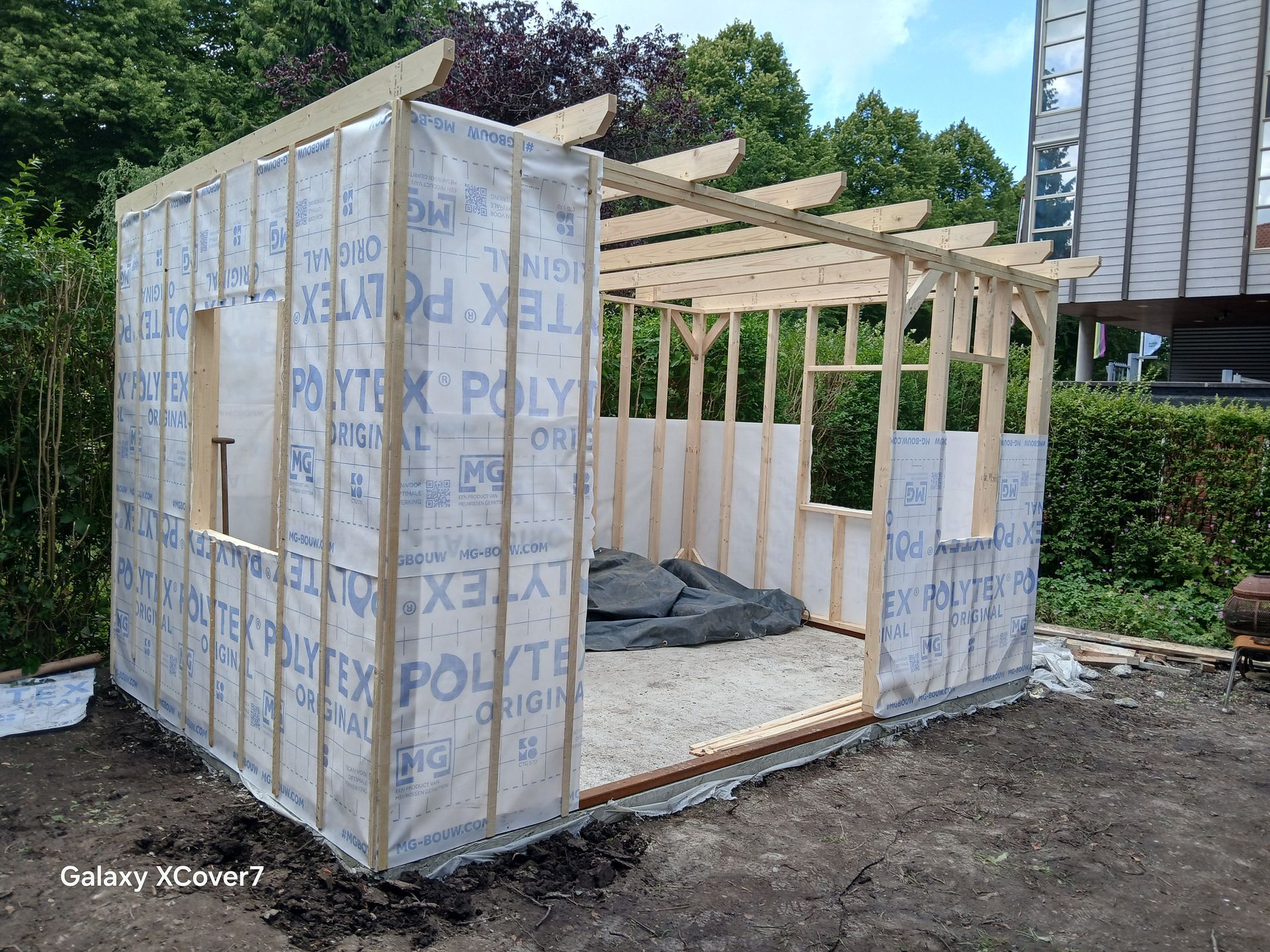 Houten frame van een schuur in aanbouw, bedekt met een dampwerende folie.
