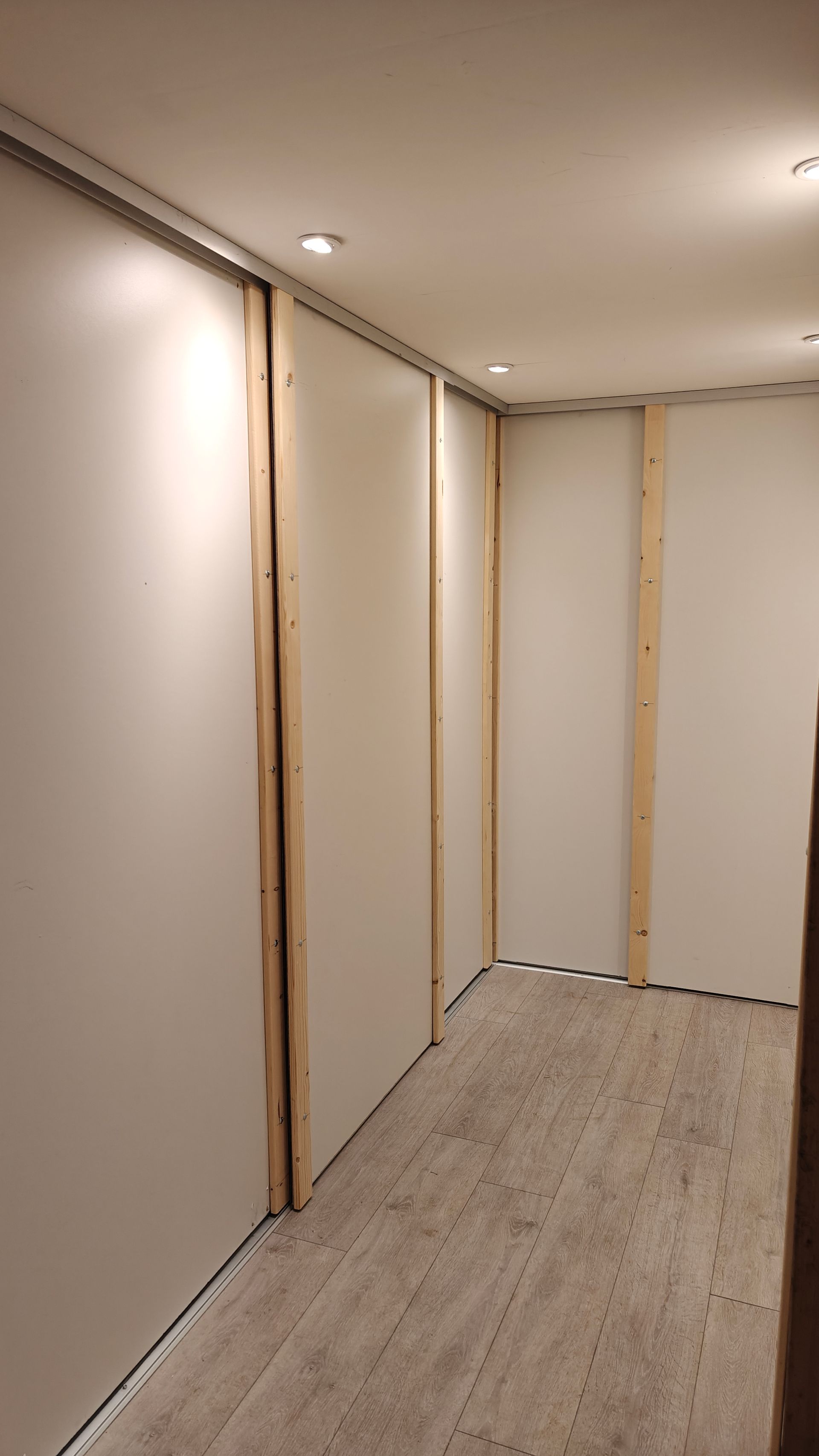 Binnenruimte met onafgewerkte muren en plafond; houten frame en beige panelen.