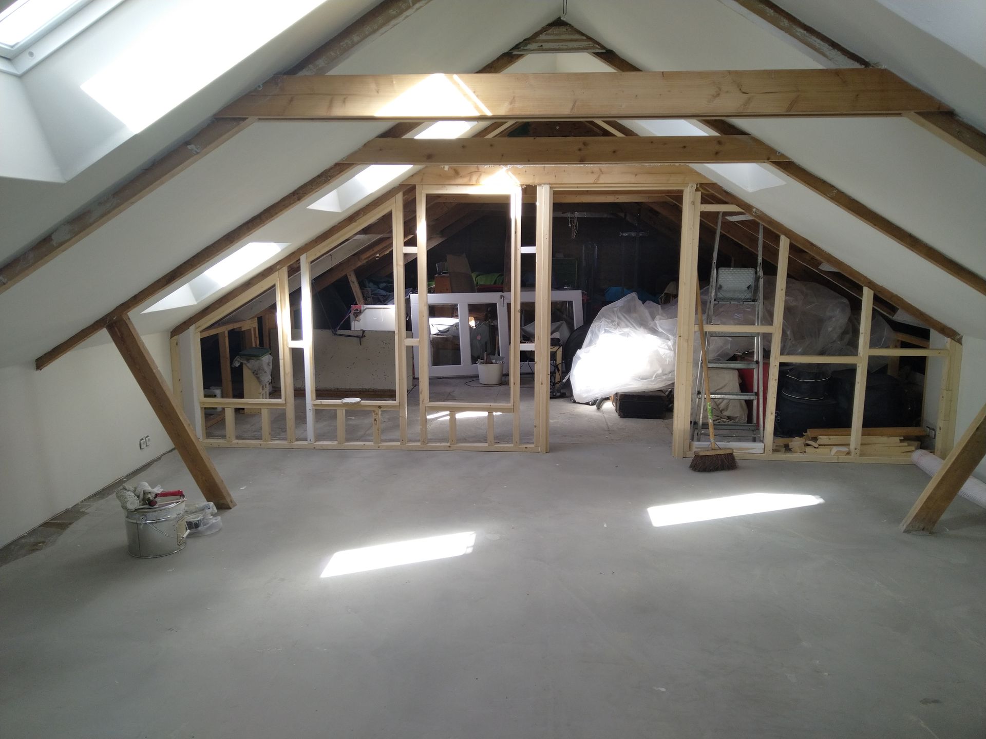 Loftinterieur in aanbouw, houten frame en zichtbare balken. Dakramen en onafgewerkte muren.