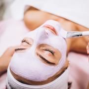 Une femme reçoit un soin du visage avec un masque blanc sur son visage.