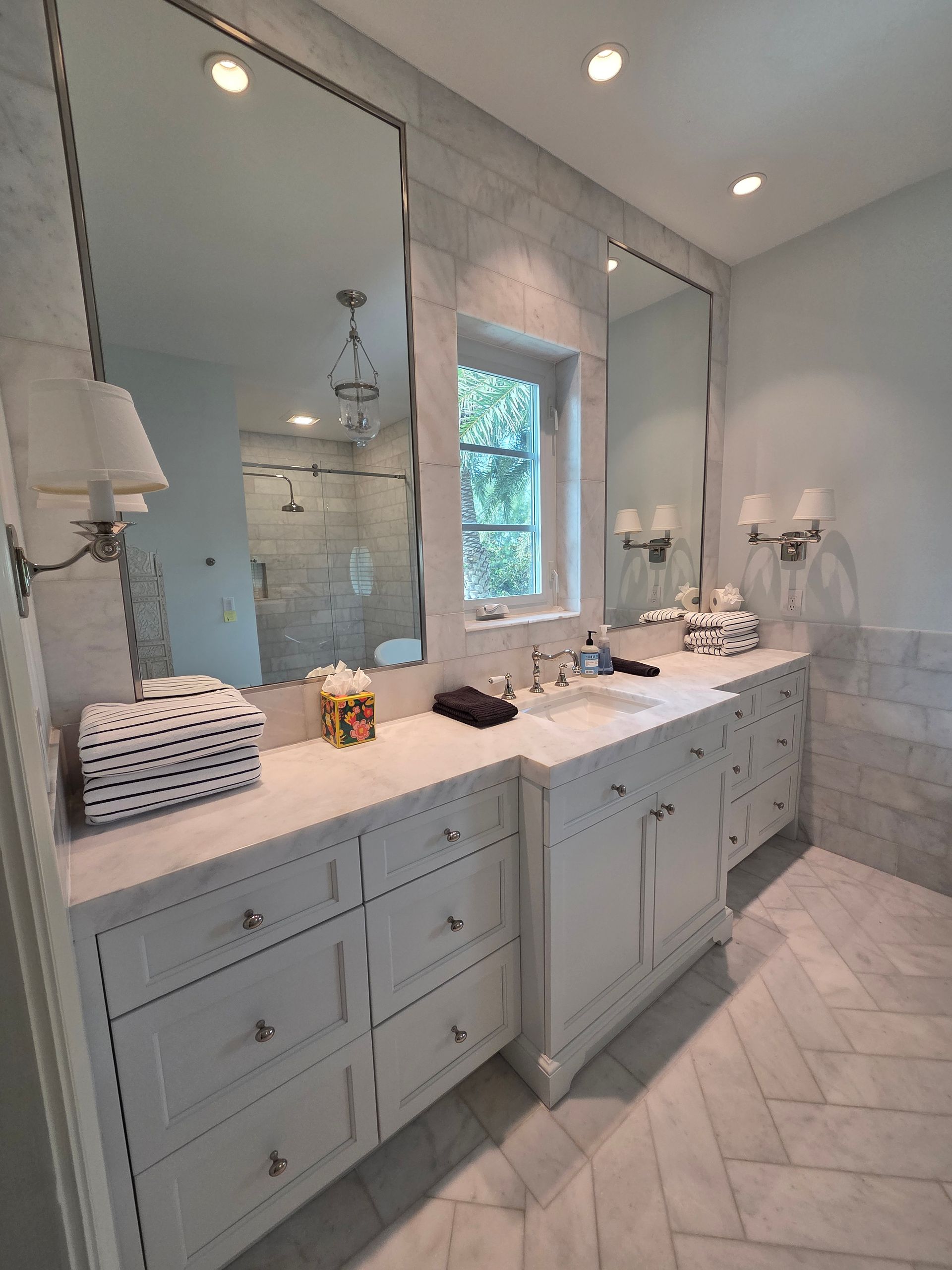 White bathroom with double vanity, two large mirrors, and herringbone floor.
